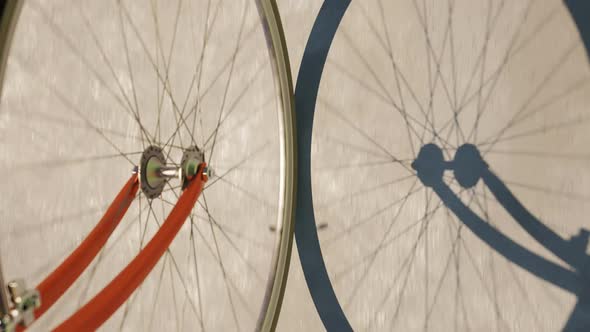 Road bike wheel spinning and casting shadow over a concrete road. Loop animation alt