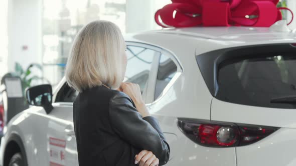 Female Customer Examining New Automobile on Sale at Auto Dealership alt