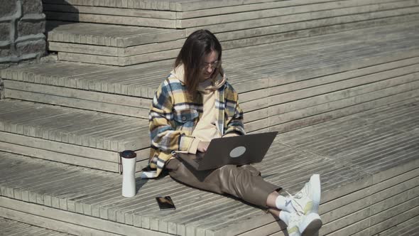 Young Woman Using Laptop While Sitting In The Street alt