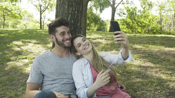Young couple listening to music and taking selfie with a smartphone alt