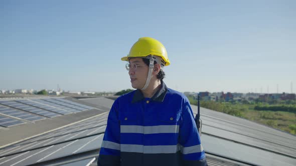 Portrait Asian engineer on field of photovoltaic solar panels solar cells on roof top factory.