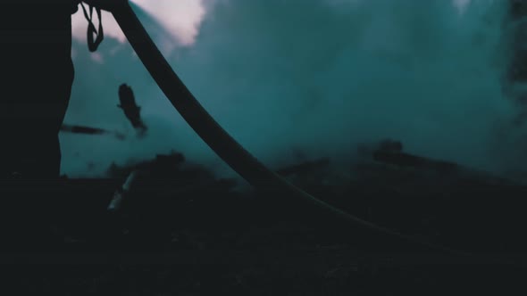 Extinguish Fire with Water By Firehose. Firefighter Hold Hose and Put Out Forest Campfire at Evening alt