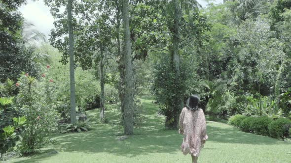 Woman Walks Through Exotic Green Garden