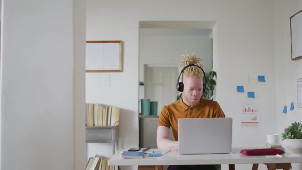 Albino african american man with dreadlocks making video call on the laptop alt