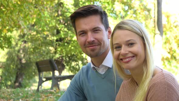 A Young Attractive Couple Smiles at the Camera in a Park on a Sunny Day - Closeup alt
