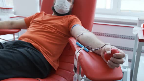 Camera Shows Blood Donor. Mature Man with Face Mask Showing Ok Sign and Looking at the Camera. Male alt