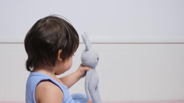 Child Is Sitting on the Bed in a T-shirt and Playing alt