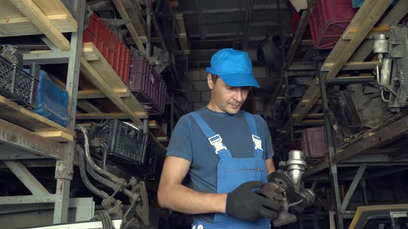 employee of auto disassembly, completes or checks car parts from tablet computer alt