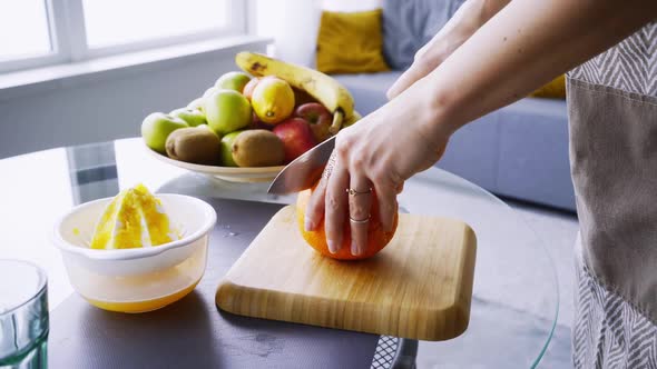 Lady Cuts Orange to Make Juice at Glass Table