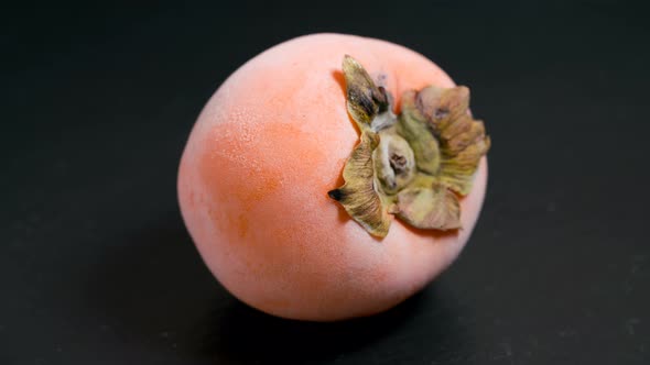 Defrosting Yellow Persimmon on a Black Background