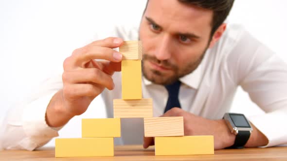Businessman playing with building blocks alt