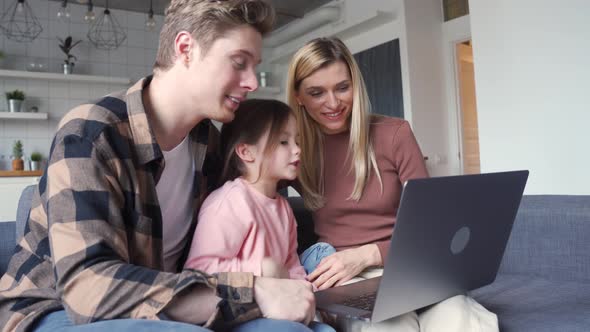 Happy Family Young Parents and Child Daughter Using Laptop Computer at Home