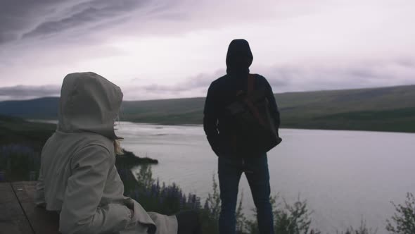 Young Couple Enjoying View of Stromy Clouds Over the Lake Cinematic Shot alt