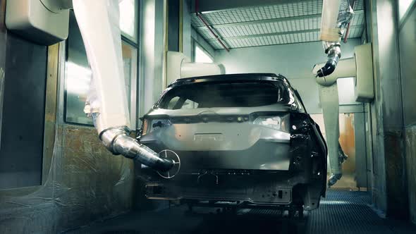 Robotic Arms Spray Painting a Vehicle Body Black at a Car Manufacturing Factory alt