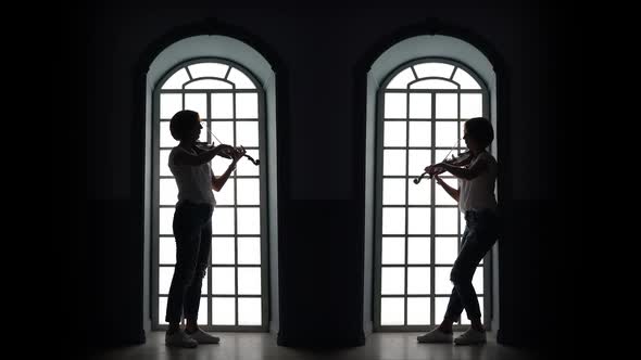 Girl Plays the Violin in the Evening Against the Background of a Window. Silhouette alt