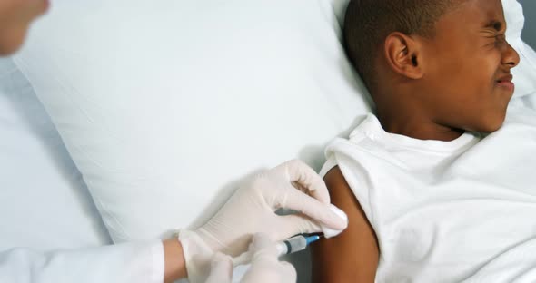 Doctor giving an injection to a boy alt