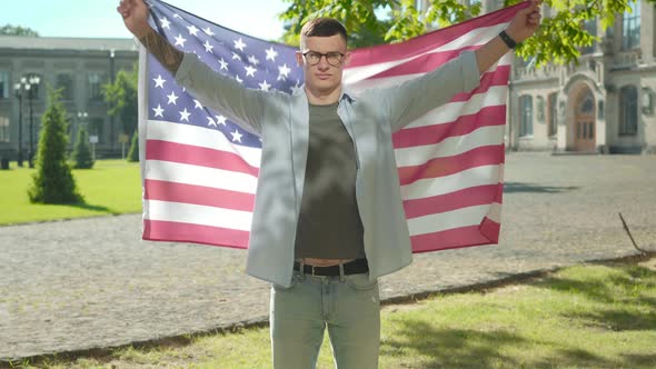 Confident Young Man Spreading Hands Holding American Flag. Portrait of Handsome Intelligent alt