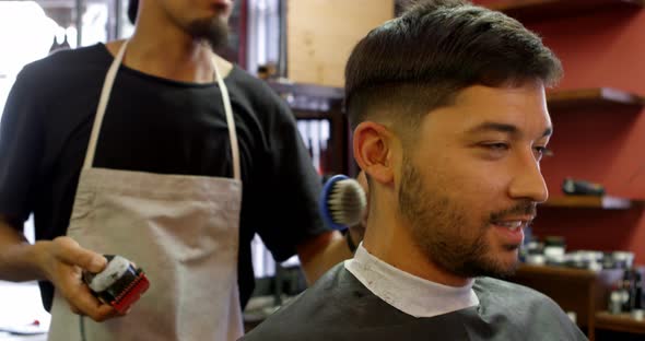Man interacting with barber while trimming his hair alt