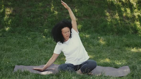 Middle Aged Woman Doing Morning Yoga Outdoors in a Park alt