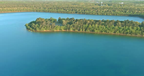 Beautiful spring nature landscape with a blue lake water between green forest alt