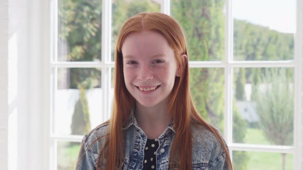 Happy Ginger Girl with Freckles Smiling Against White Window alt