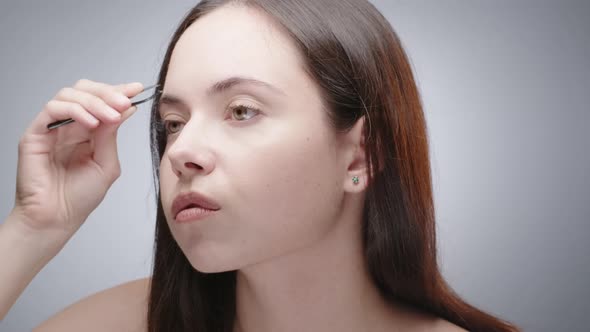 Woman Correcting Brows with Tweezers alt