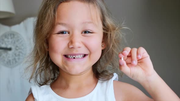 Portrait of Little Child Girl Is Showing Her Lost Milk Tooth and Smiling