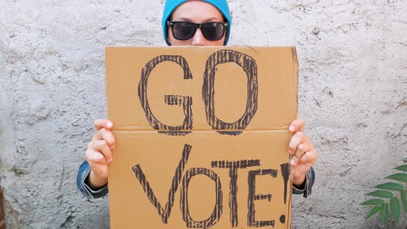 Woman shows cardboard Go Vote sign Voting balloting polling Political choice elections voice 4K