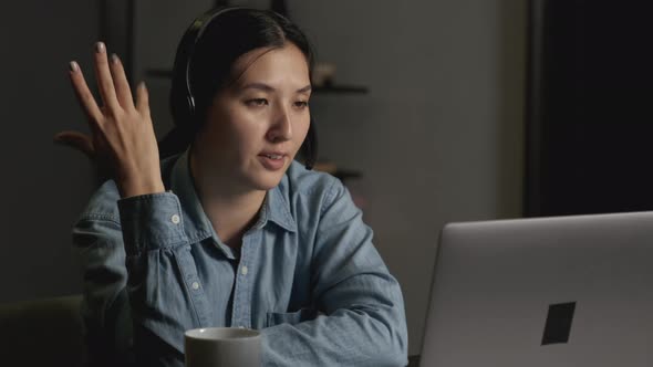 Close-Up of a Young Asian Woman Smiling in Headphones with a Microphone for Work alt