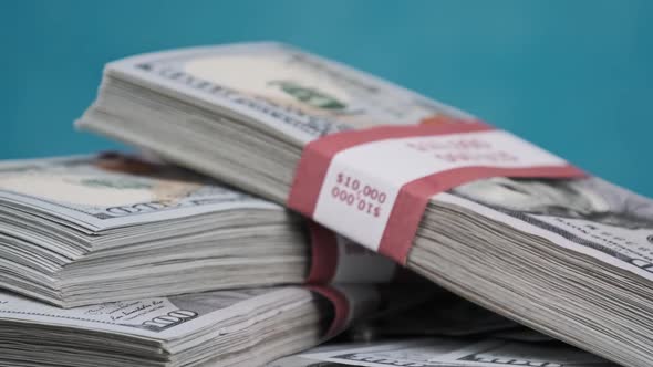 Bundles of Dollars Lying on a Pile of Money and Rotate on Blue Background alt
