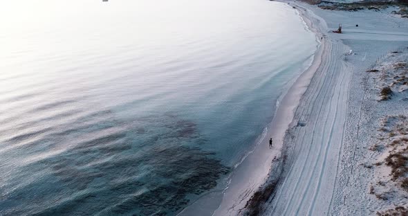 One man walking at the beach in soft morning light with blue transparent water on his side. People alt