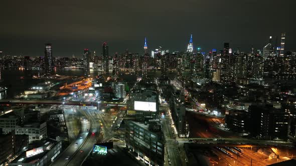 An aerial view from over Long Island City, New York at night. The drone camera dolly in slowly facin alt