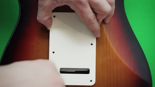 Man screws guitar backplate 4K alt