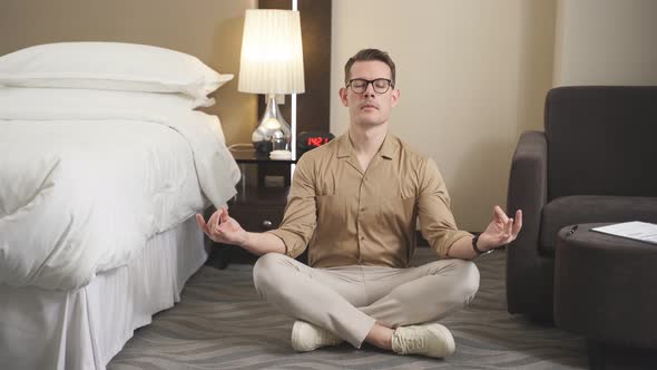 Calm Serious Guy In Stylish Wear Sit On Hotel Room Floor Meditating