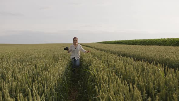 Smiling Girl Running in the Greenyellow Wheat Filed alt