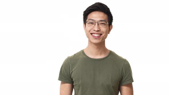 Portrait of Pleased Asian Man Wearing Eyeglasses and Basic Tshirt Grinning with Bright Smile alt