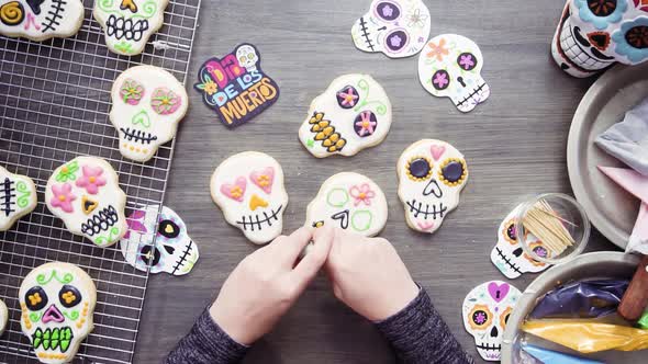Step by step. Flat lay. Decorating sugar skull cookies with different color royal icing. alt