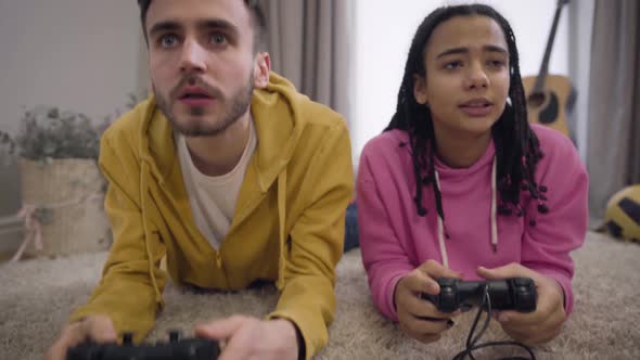 Camera Zooming in and Moving Up Showing Two Cheerful Friends Using Gaming Console, Giving High Five alt