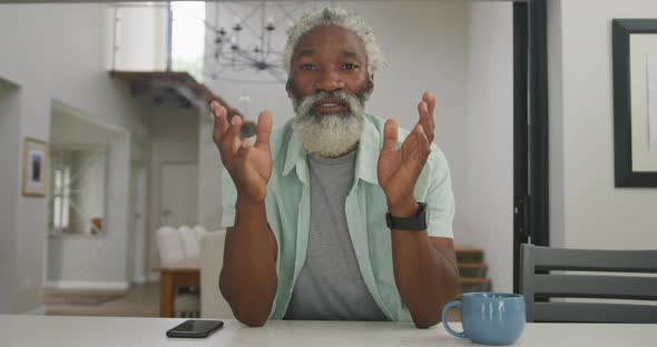 Video of happy african american senior man drinking coffee alt