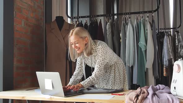 Happy Tailor in Workplace Uses Laptop To Sign Lucrative Contract alt