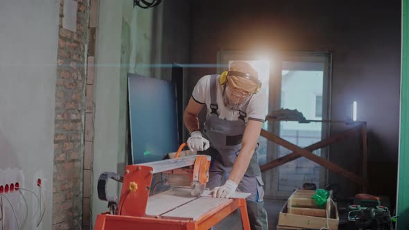Male Builder Uses Electric Tile Cutter in Construction Studio