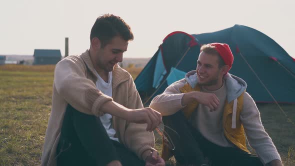 Smiling Men Talk Resting at Blue Tent in Camp on Meadow alt
