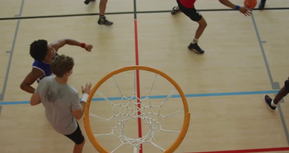 Overhead view of african american male basketball player scoring goal against diverse players alt