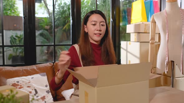 Young Asian woman put cloth or dress into parcel or plastic back then pack in box or carton