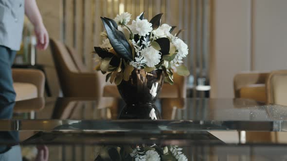 The Maid Puts a Vase of Fresh Flowers on the Table