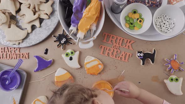 Step by step. Mother and daughter decorating Halloween sugar cookies with colorful royal icing. alt