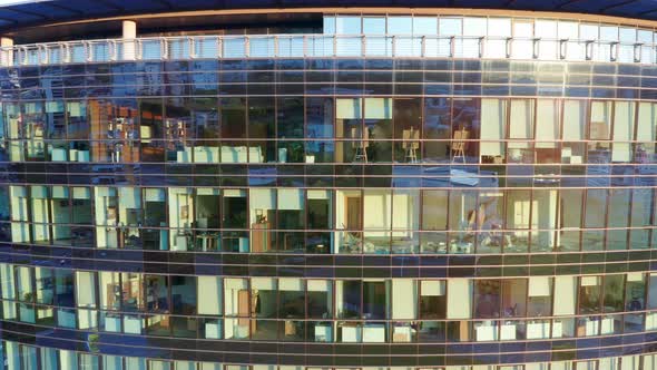 Offices in a modern high rise commercial building with glass facade at sunset alt