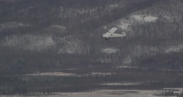 Aerial helicopter shot up and around hilltop, frozen pine trees, valley in distance, drone footage alt