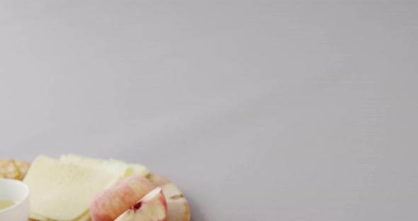 Different types of cheese, crispy biscuits, fruits and sauce on wooden board alt