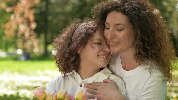 Portrait of a Woman with a Bouquet of Tulips Hugging Her Teenage Daughter
